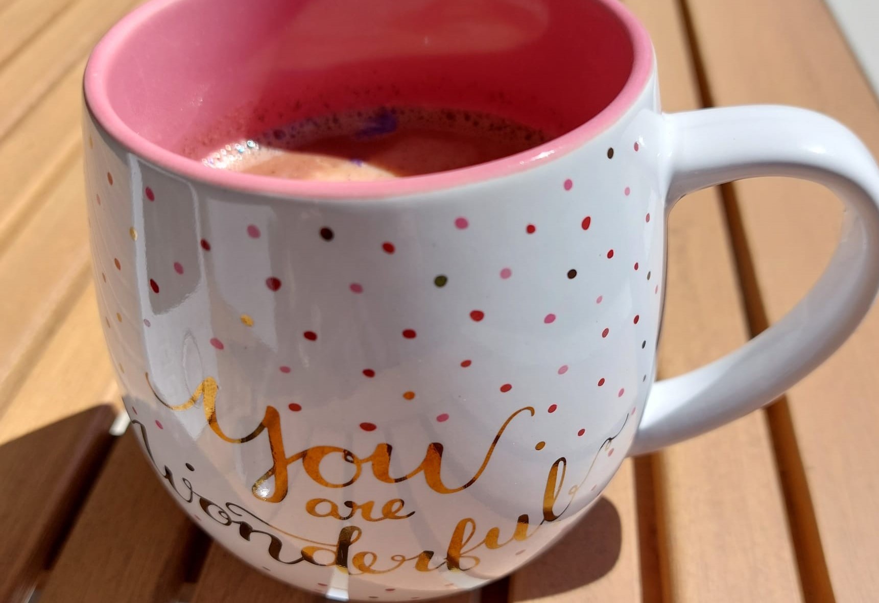 Bewusstseins-Café VorschauBild bauchig runde Tasse mit bunten Pünktchen mit goldener Schrift You are wonderful Kakao mit Blütenessenz Holztisch Sonnenschein